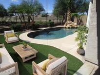 Relaxing kidney-shaped pool with patio furniture and lush landscaping at 3919 E Blue Sage Rd, Gilbert, AZ 85297