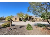 Tan house with tile roof, landscaping, and long driveway at 6416 W Parkside Ln, Glendale, AZ 85310