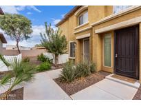 Tan two-story townhome with a walkway, landscaping, and a dark brown door at 7820 E Baseline Rd # 103, Mesa, AZ 85209