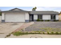 Charming single-story home with a two-car garage, gravel yard, and a welcoming front entrance at 13804 N 52Nd Dr, Glendale, AZ 85306