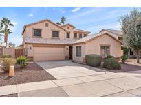 Two story house with a tan facade, two car garage, and landscaped yard at 8147 W Hilton Ave, Phoenix, AZ 85043