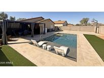 Inviting backyard pool with artificial grass, modern lounge chairs, and a charming shaded pergola at 1164 E Desert Rose Trl, San Tan Valley, AZ 85143