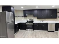 A renovated kitchen with stainless steel appliances, white countertops, and dark cabinetry stands ready for a new owner at 1983 E Don Carlos Ave, Tempe, AZ 85281