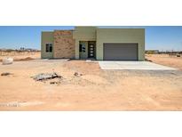 Modern, light green, single-story home with a stylish stone accent wall and grey garage door at 28583 N 257Th Dr, Wittmann, AZ 85361