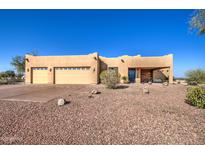 Single-story stucco home with three-car garage and desert landscaping at 20040 W Hunter Dr, Wittmann, AZ 85361