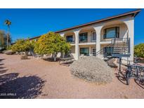 Exterior view of a two-story building with balconies, landscaping, and a stairway at 3270 S Goldfield Rd # 816, Apache Junction, AZ 85119