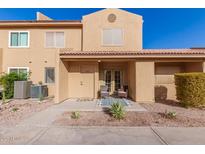 Tan two-story stucco home with front patio and two chairs at 3511 E Baseline Rd # 1206, Phoenix, AZ 85042