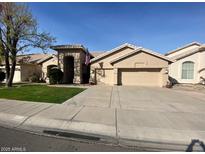 Tan two-story house with a three-car garage and manicured lawn at 5184 W Del Rio St, Chandler, AZ 85226