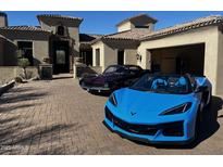 A beige stucco home with a beautiful brick driveway showing off classic and modern sports cars at 3254 N Ladera Cir, Mesa, AZ 85207