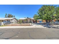 Tan single story home with a spacious yard and mature tree at 7201 W Alvarado Rd, Phoenix, AZ 85035