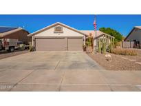 Single-story home featuring a desert landscape, a two-car garage, and an American flag at 18014 N 63Rd Ln, Glendale, AZ 85308