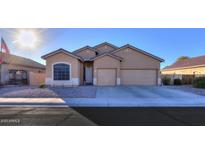 One-story house with tan exterior, two-car garage, and landscaped front yard at 22488 N Mulligan Dr, Maricopa, AZ 85138