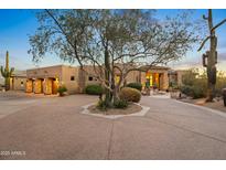 Stunning desert home with circular driveway, mature trees, and landscape lighting at 23238 N 94Th Pl, Scottsdale, AZ 85255