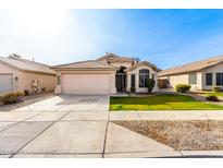One-story house with beige exterior, landscaped lawn, and a two-car garage at 3037 E Roveen Ave, Phoenix, AZ 85032