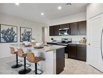 Modern kitchen with dark cabinetry, granite countertops, and island with seating at 5697 E Clandestine Dr, San Tan Valley, AZ 85140