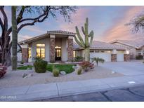 Beautiful single-story home featuring desert landscaping, stone accents, and a three-car garage at 8900 E Palm Tree Dr, Scottsdale, AZ 85255