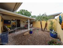 Cozy back patio with desert landscaping, covered area with chairs, and sliding glass doors to interior at 10407 N 108Th Ave, Sun City, AZ 85351