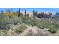 Desert landscape surrounds this single-story home with stucco exterior and covered patio at 55823 N 329Th Dr, Wickenburg, AZ 85390