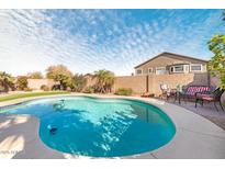 Inviting kidney-shaped pool with patio and grassy area at 5613 N Laguna Ct, Litchfield Park, AZ 85340