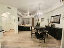 Bright, open-concept living room with light wood floors and elegant chandelier at 14575 W Mountain View Blvd # 11210, Surprise, AZ 85374