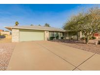 House exterior featuring a light green single story home with a two car garage and a neatly landscaped yard at 12734 W Crystal Lake Dr, Sun City West, AZ 85375