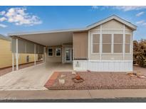 Tan mobile home with covered carport and landscaped yard at 111 S Greenfield Rd # 827, Mesa, AZ 85206