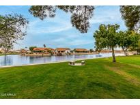 Picturesque community lake view with green grass and neighborhood houses in a tranquil setting at 10971 W Tonopah Dr, Peoria, AZ 85373