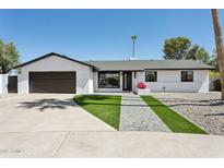 Charming home featuring a well-manicured front yard, lush lawn, and a classic black and white color scheme at 2217 N 79Th St, Scottsdale, AZ 85257