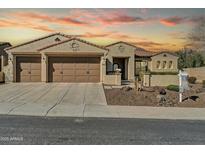 Inviting home featuring a 3-car garage, desert landscaping, and classic Southwestern architecture at sunset at 30696 N 130Th Ln, Peoria, AZ 85383