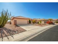 Tan house with a two-car garage and cacti in the front yard at 16331 W Willow Creek Ln, Surprise, AZ 85374