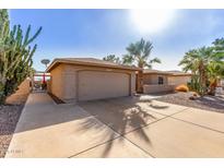 Home's exterior features a two-car garage, desert landscaping, and a well-maintained driveway at 9725 E Navajo Pl, Sun Lakes, AZ 85248