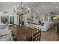 Bright, open-concept living area with a dining table, fireplace, and modern chandelier at 10685 E Cinnabar Ave, Scottsdale, AZ 85258