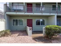 Two-story condo featuring a red door, large windows, and rock landscaping at 1702 W Tuckey Ln # 123, Phoenix, AZ 85015