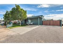 Charming single-story home featuring desert landscaping, mature trees and a covered front porch seating area at 10433 E Boise St, Apache Junction, AZ 85120