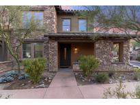 Charming stone-clad home featuring a welcoming front porch and an elegant dark wood door at 17763 N 93Rd Way, Scottsdale, AZ 85255