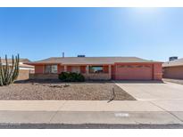 Single story home with peach stucco exterior, two-car garage, and desert landscaping at 11029 W Meade Dr, Sun City, AZ 85351