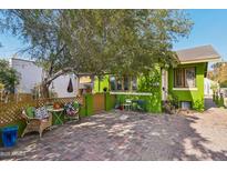 Charming green home featuring a brick driveway, a large shade tree and outdoor seating area at 1638 E Earll Dr, Phoenix, AZ 85016