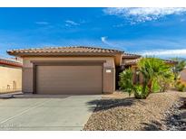 Tan house with a two-car garage and desert landscaping at 18727 N Desert Light Dr, Surprise, AZ 85387