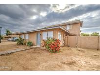 Tan two-story building with gray door, red flowers, and a walkway at 4242 N 69Th Dr # 1303, Phoenix, AZ 85033