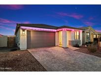 Charming home exterior featuring stylish brick driveway, two-car garage, and vibrant pink accent lights at 11517 E Unity Ave, Mesa, AZ 85212