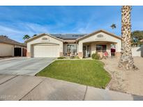 Single-story home with a landscaped lawn, two-car garage, and solar panels at 12858 W Wilshire Dr, Avondale, AZ 85392