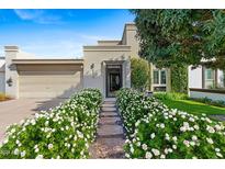 Tan two-story house with a nicely landscaped front yard, stone pathway, and attached garage at 6314 E Pinchot Ave, Scottsdale, AZ 85251