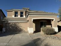 Two-story house with tan exterior, two-car garage, and landscaped front yard at 15118 W Lincoln St St, Goodyear, AZ 85338