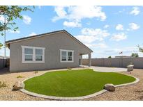 Landscaped backyard features synthetic grass, stone accents, and a covered patio perfect for outdoor relaxation and entertainment at 18864 E Bruno Dr, Gold Canyon, AZ 85118