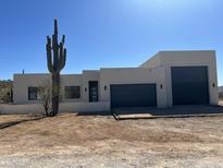 Modern home featuring a neutral stucco exterior, a large Saguaro cactus, and a two-car garage at 431 W Rough Rider Rd, New River, AZ 85087