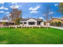 Charming home with a manicured front lawn, white brick exterior, and black shutters under a blue sky at 412 W Vermont W Ave, Phoenix, AZ 85013