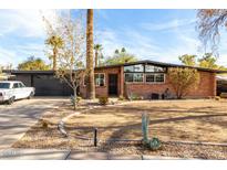 Charming brick home with a well-manicured lawn, mature trees, and a classic car in the driveway at 901 W Heather Dr, Mesa, AZ 85201