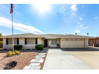 White brick ranch home with landscaped yard, two-car garage, and flagpole at 9719 W Newport Dr, Sun City, AZ 85351