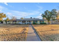 Charming single-story home with a welcoming front porch, mature trees, and expansive front yard at 2011 W Cambridge Ave, Phoenix, AZ 85009
