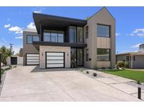 Striking modern home featuring a two-tone facade, balcony, and a spacious concrete driveway at 4445 E Roma Ave, Phoenix, AZ 85018